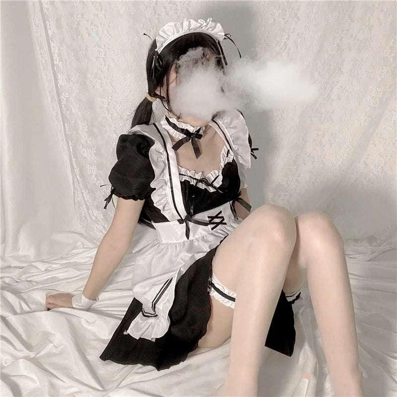Femme portant une robe de maid Lolita noire et blanche assise sur un lit avec fond blanc